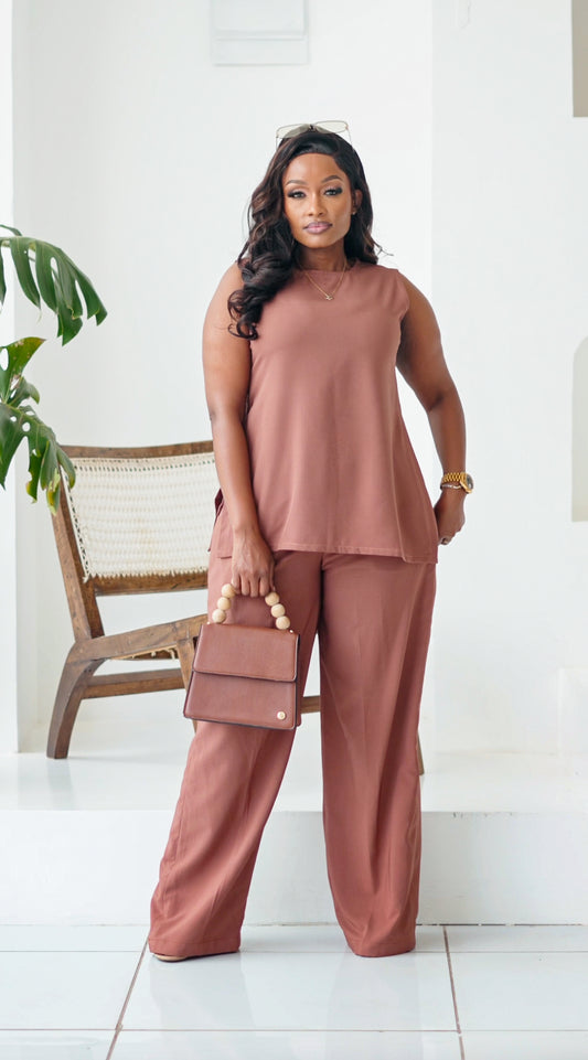 Woman in a matching outfit with a handbag standing in a minimalistic room.