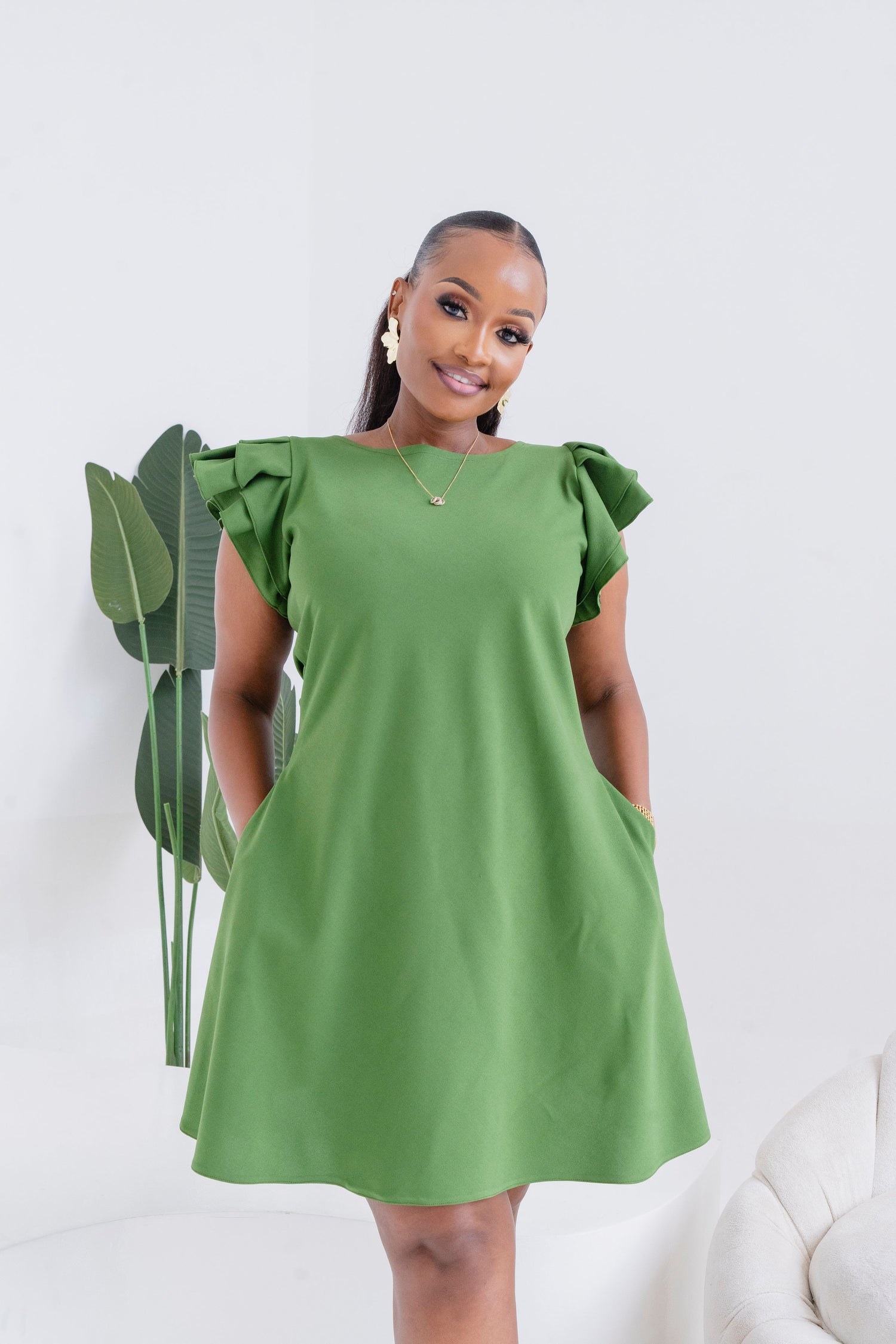 Woman wearing a green dress with ruffled sleeves against a white background