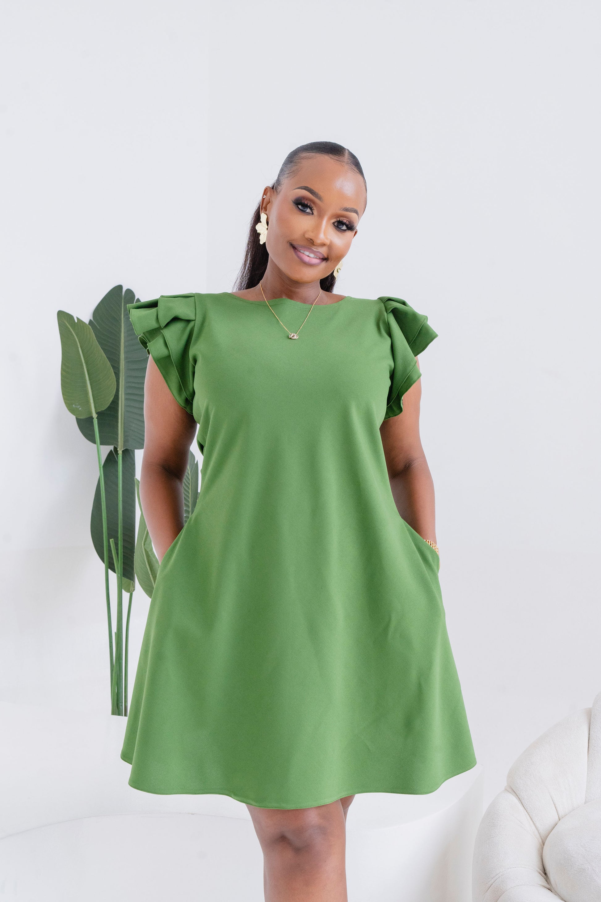 Woman wearing a green dress with ruffled sleeves against a white background