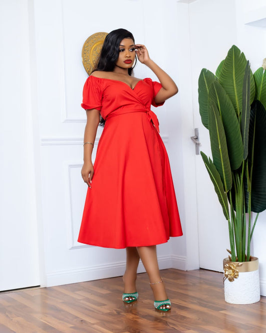 Woman in a red dress standing indoors with a plant in the background